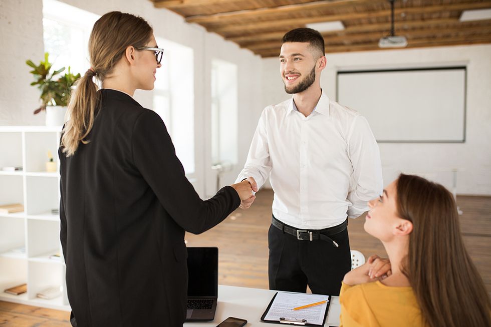 Recent college grad goes in for a job interview and shakes hands with the hiring manager