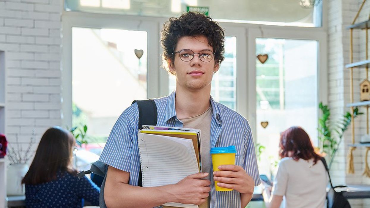 Recent college grad holding a notebook and coffee thinks about getting a job