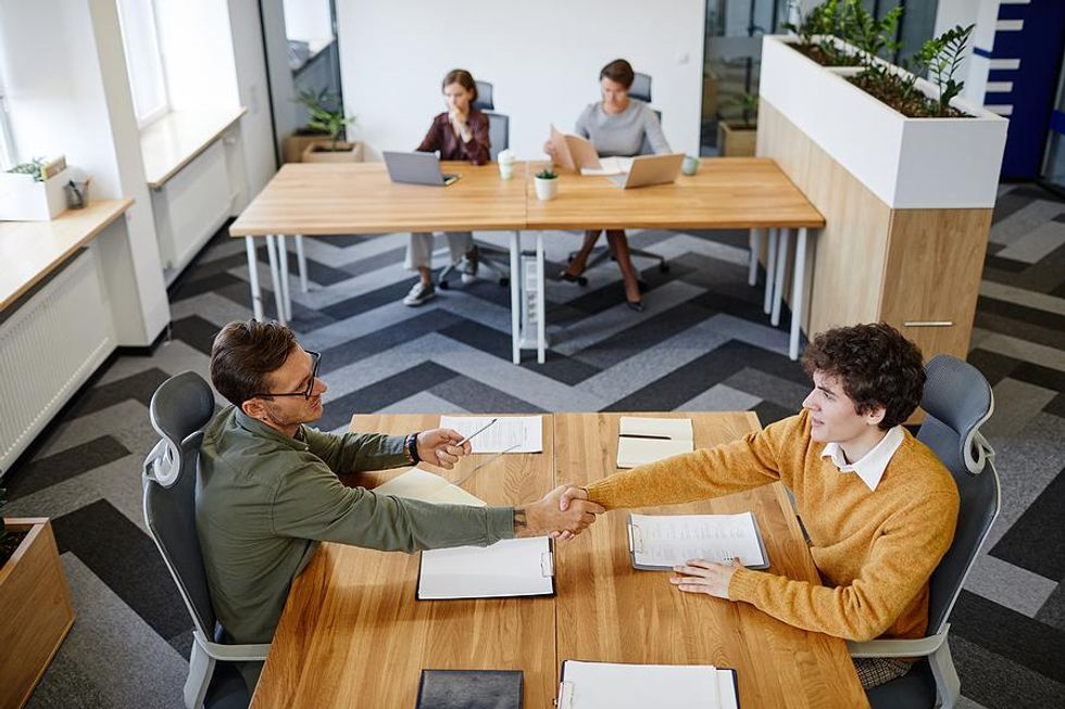 Recent college grad shakes hands with the hiring manager after a job interview