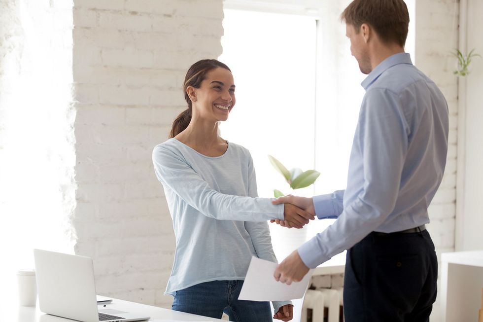Recent college grad shakes the hand of the hiring manager after a job interview