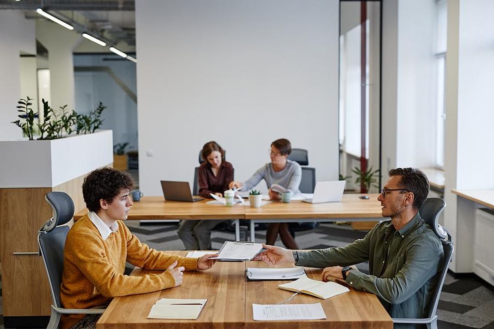 Recent college grad talks to his boss at an entry-level job