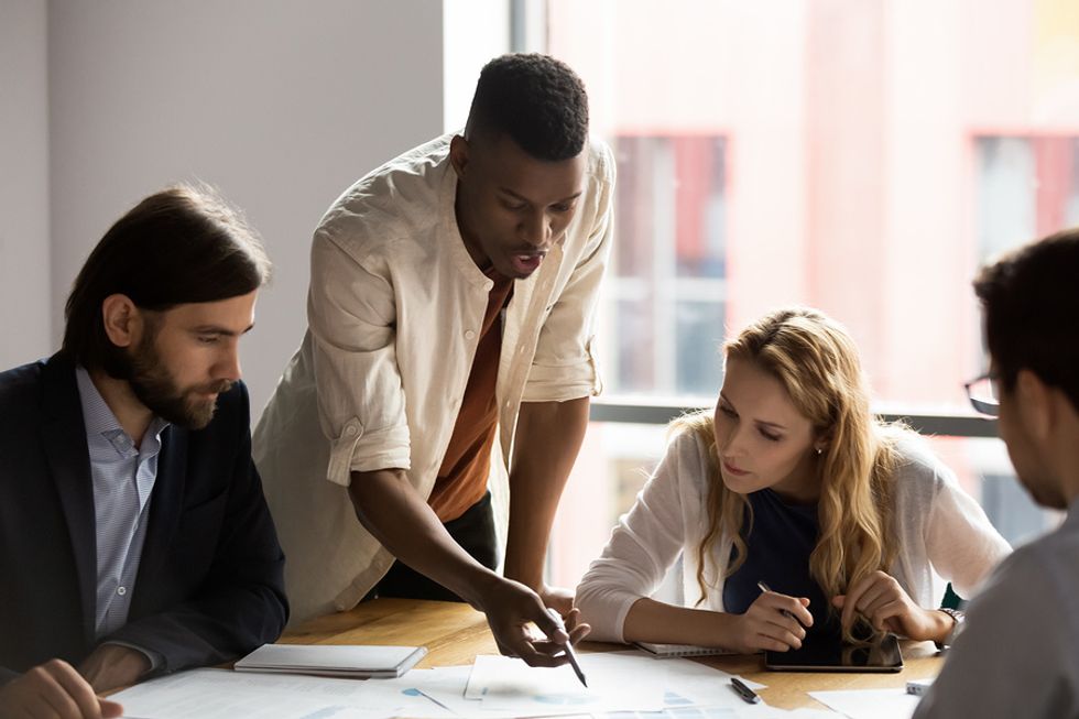 Recent college graduate works at his internship / talks during a meeting