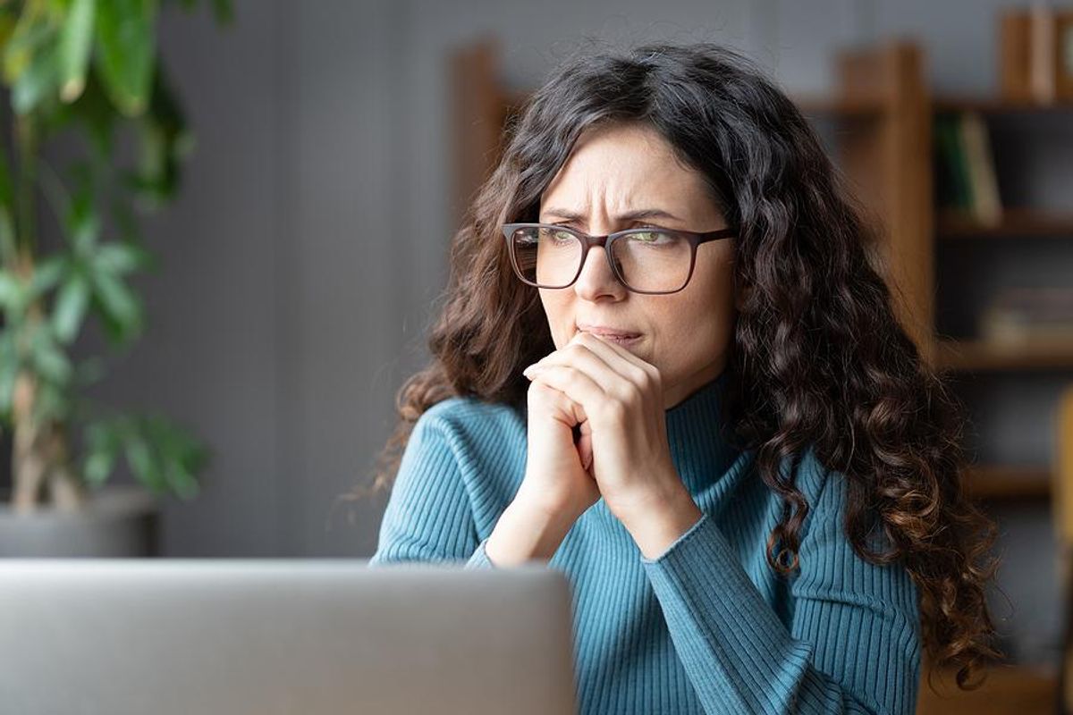 Serious/stressed/anxious woman on laptop thinking about a recession