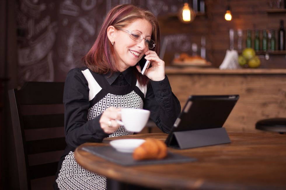 smiling businesswoman while talking on the phone in front of tablet