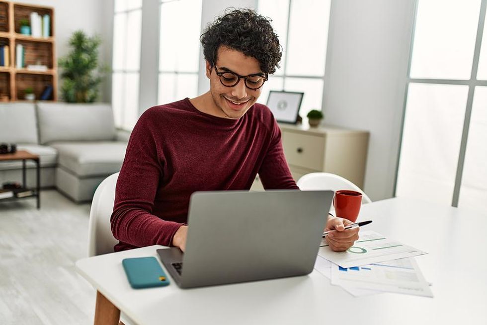 Smiling man writes down his career goals and resolutions on his laptop