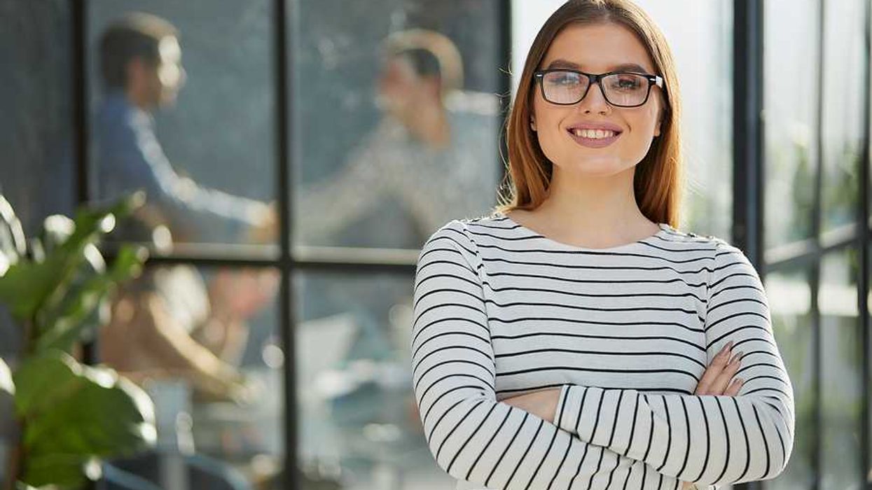 Smiling, professional woman stands with her arms crossed as she thinks about finding her purpose