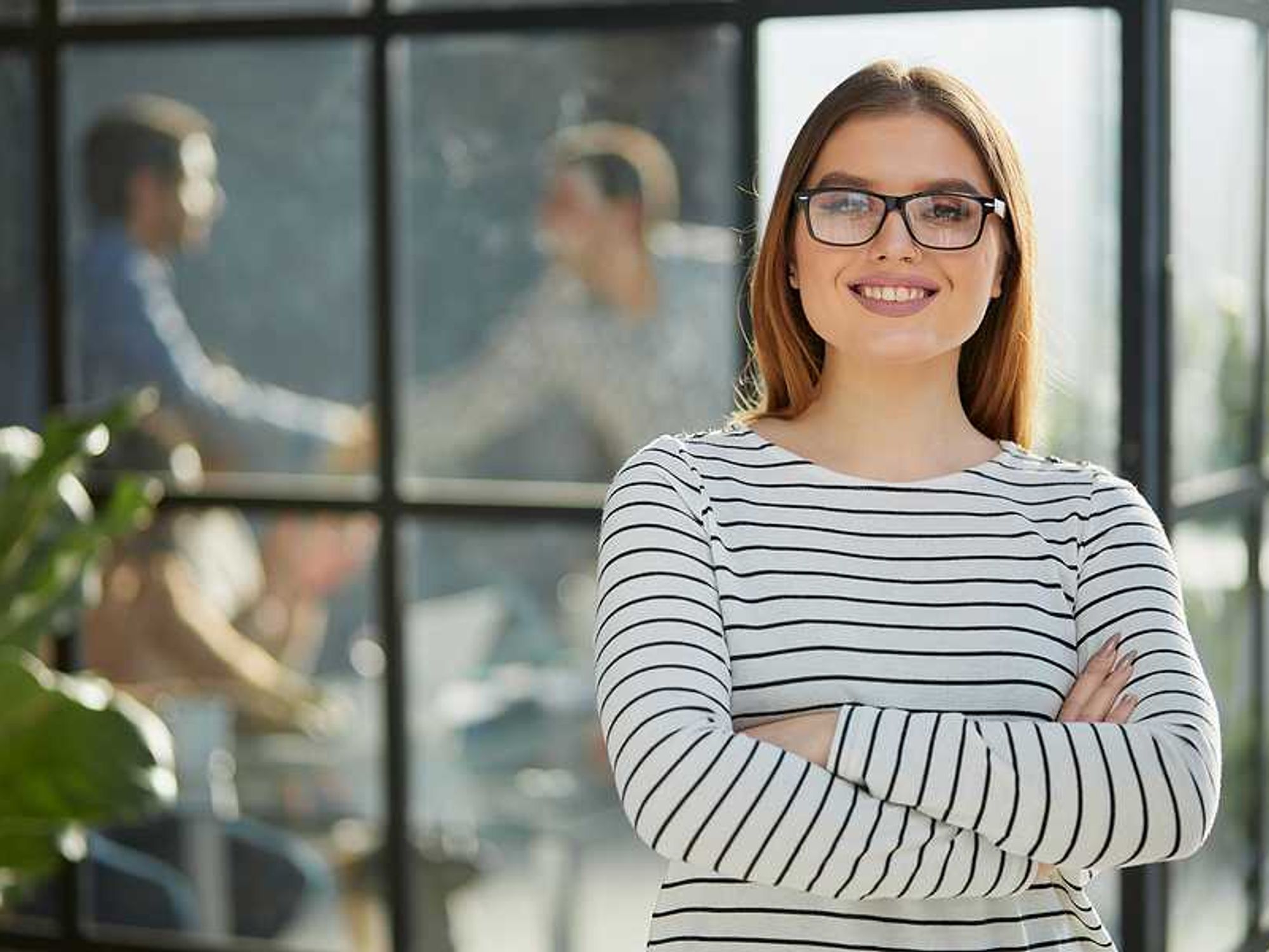 Smiling, professional woman stands with her arms crossed as she thinks about finding her purpose