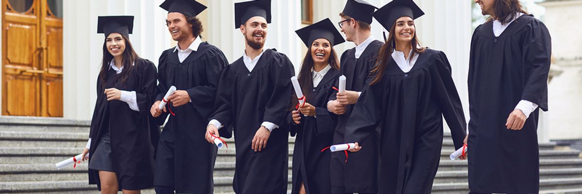 Smiling recent college grads walking in a group with their diplomas