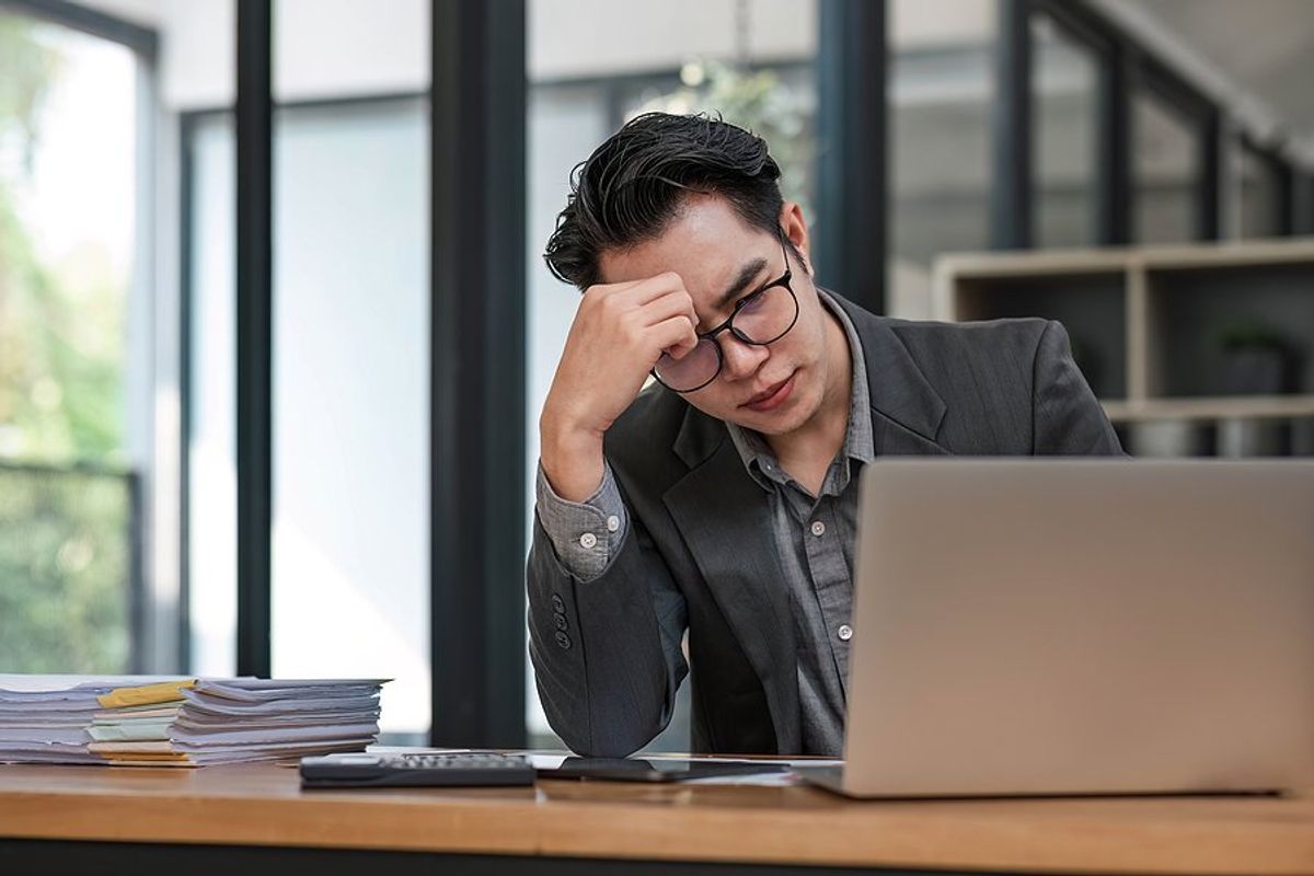 Stressed man at work looks at his laptop