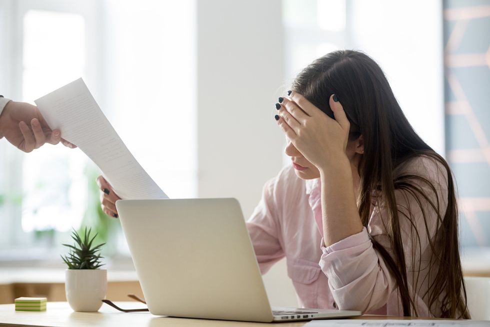 Stressed woman on laptop gets laid off from her job