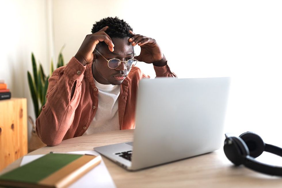 Stressed young professional/recent college grad on laptop tries to find a job while unemployed