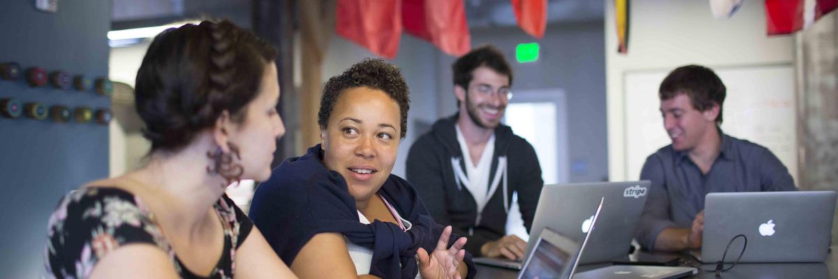Stripe employees collaborate as flags from around the globe hang in the background.