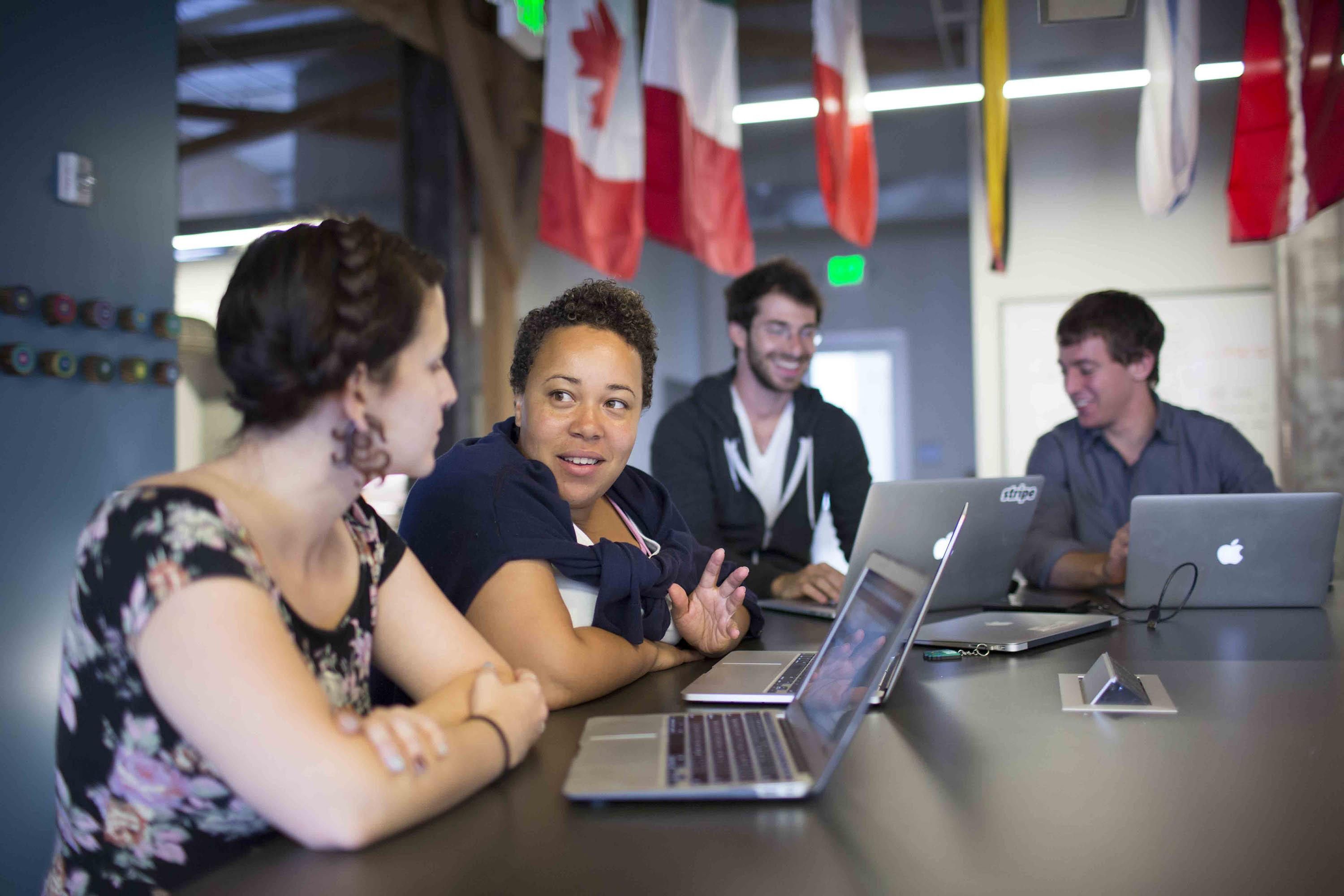 Stripe employees collaborate as flags from around the globe hang in the background.