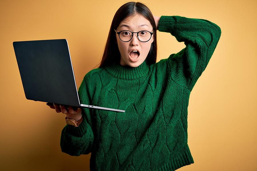 Surprised woman holding laptop dealing with job search fears