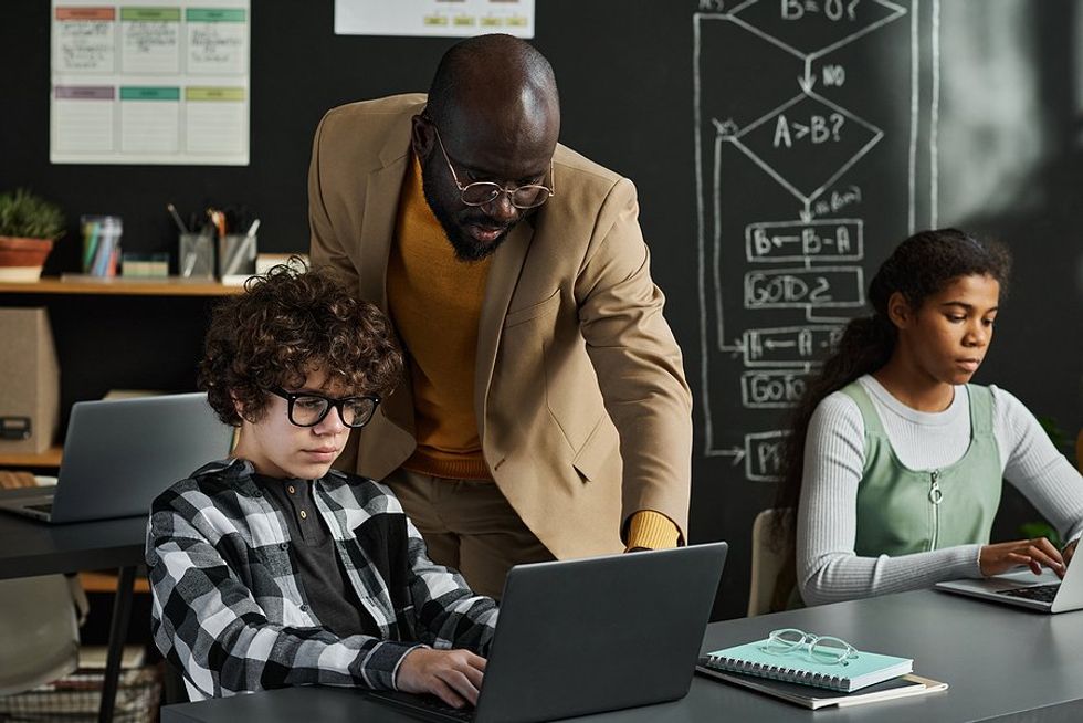 Teacher helps a student in his classroom