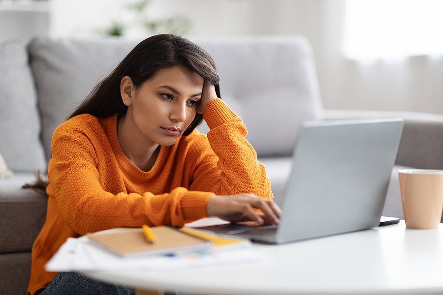 Tired/exhausted/bored/frustrated woman on laptop deals with remote work loneliness