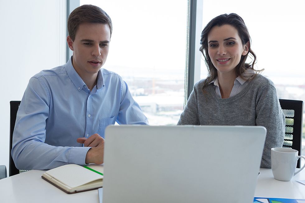 Two co-workers collaborate together to solve a problem.