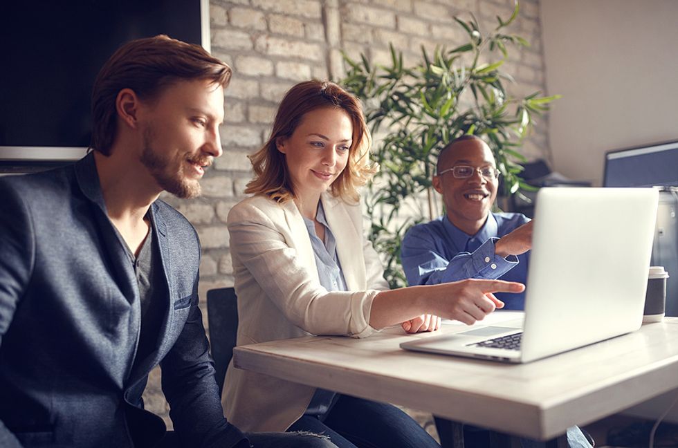 Two co-workers go over some ideas with their boss during a meeting