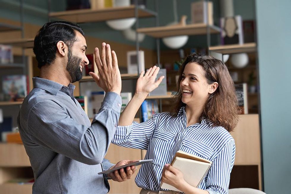 Two coworkers high-five and network together