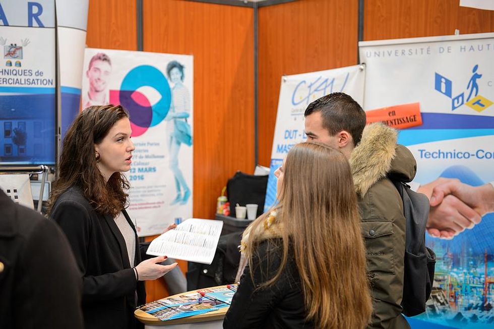 Two job seekers talk to an employer at a job fair