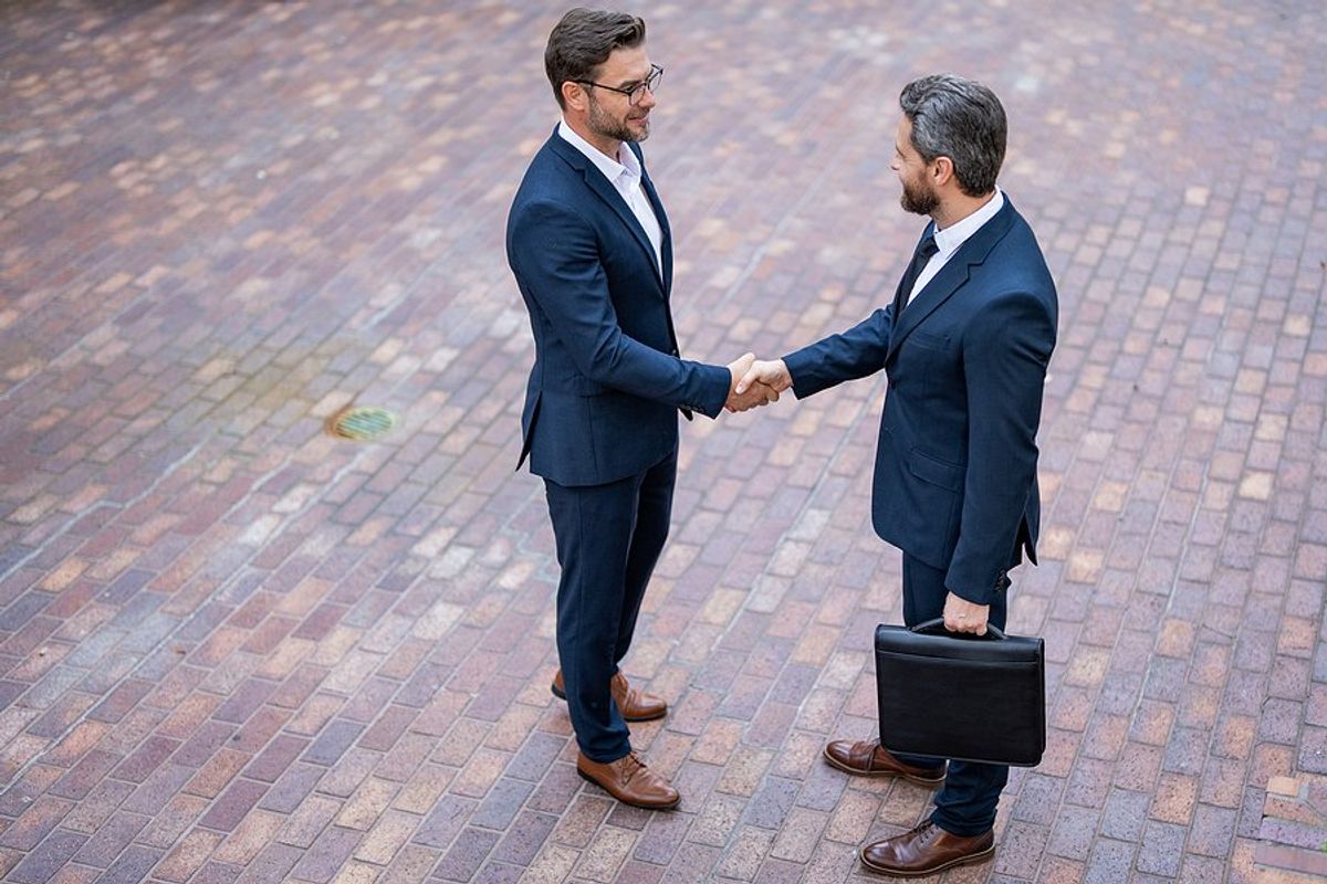 Two professionals/executives/leaders shake hands and successfully manage their business relationship