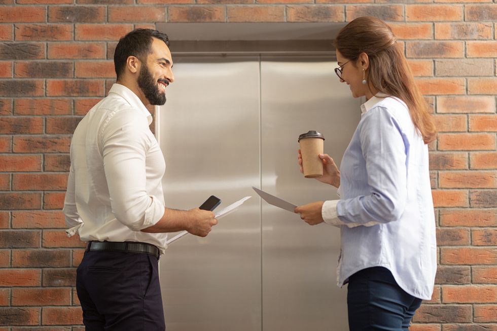 Two professionals flirt while waiting for the elevator