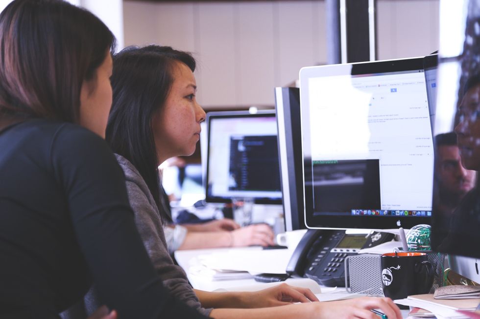 Two professionals help each other with their LinkedIn profiles.