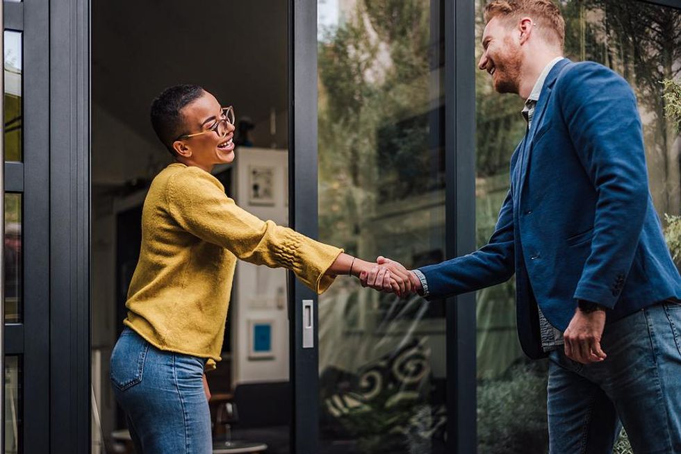 Two professionals shake hands and smile at each other