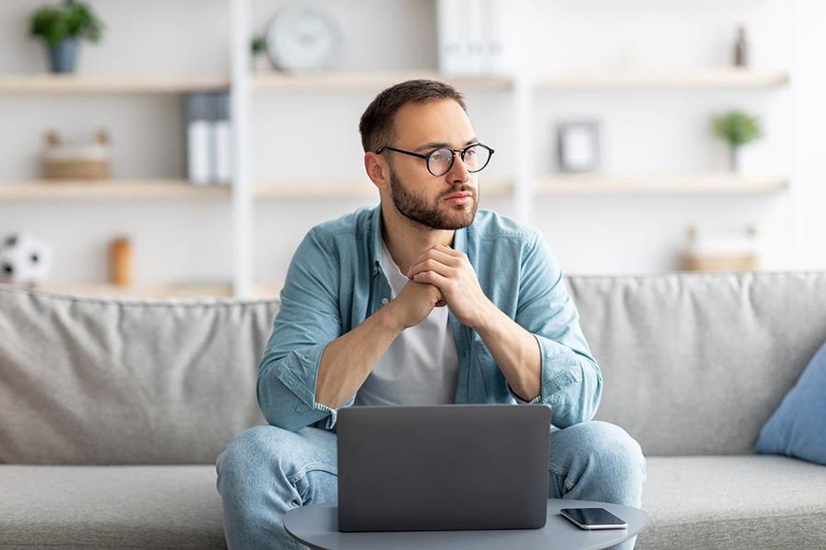 Unemployed man on laptop thinks about what to do while unemployed