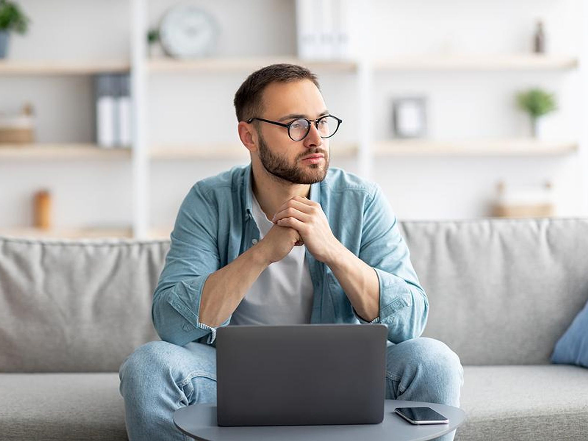 Unemployed man on laptop thinks about what to do while unemployed
