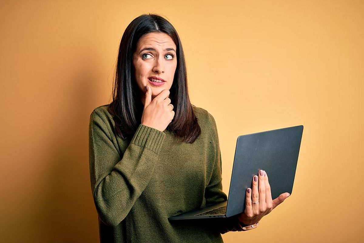 Woman confused while writing her resume on her laptop