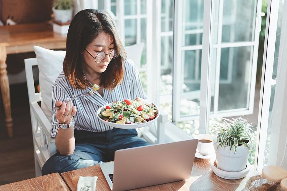 Woman eats lunch while working from home