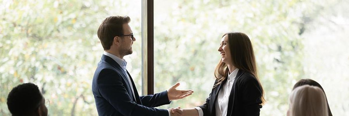 Woman gets a promotion at work and shakes hands with her new boss