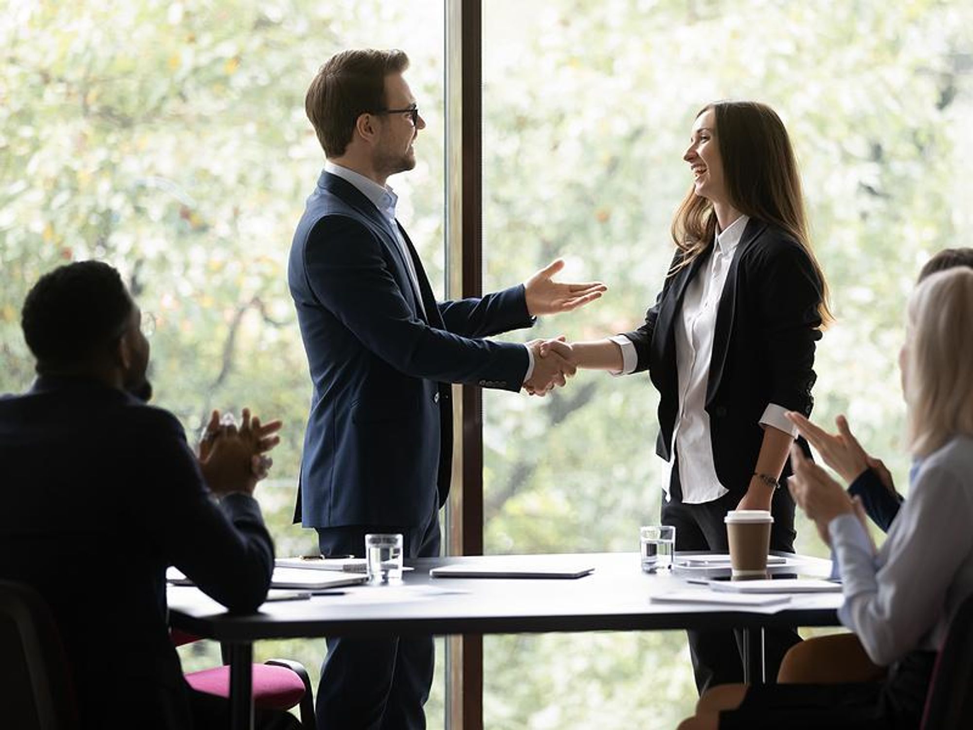 Woman gets a promotion at work and shakes hands with her new boss