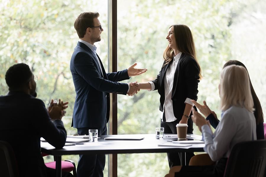 Woman gets a promotion at work and shakes hands with her new boss