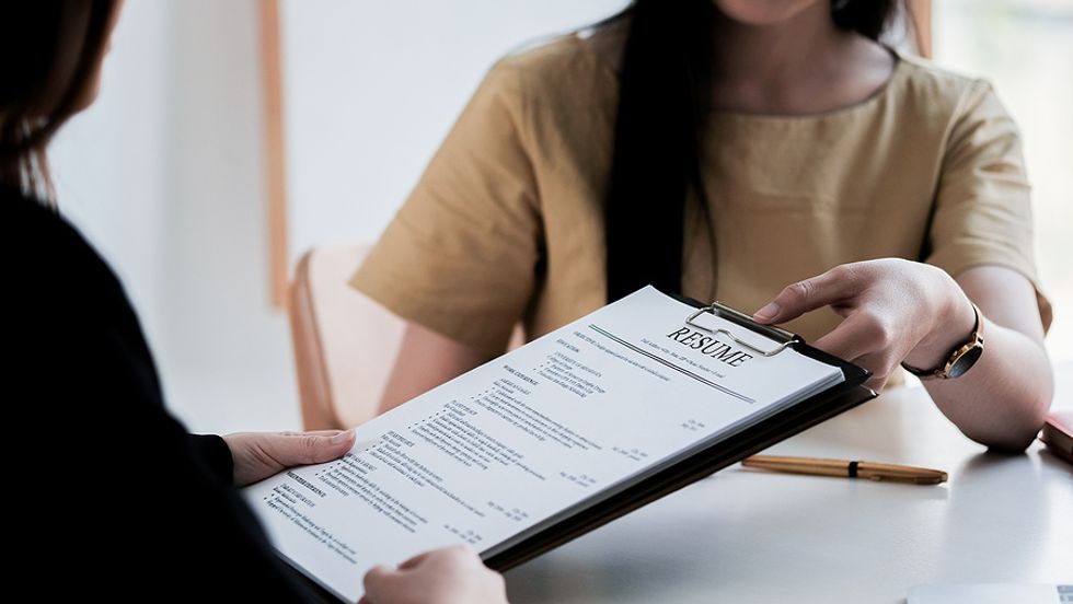 Woman hands the hiring manager a resume