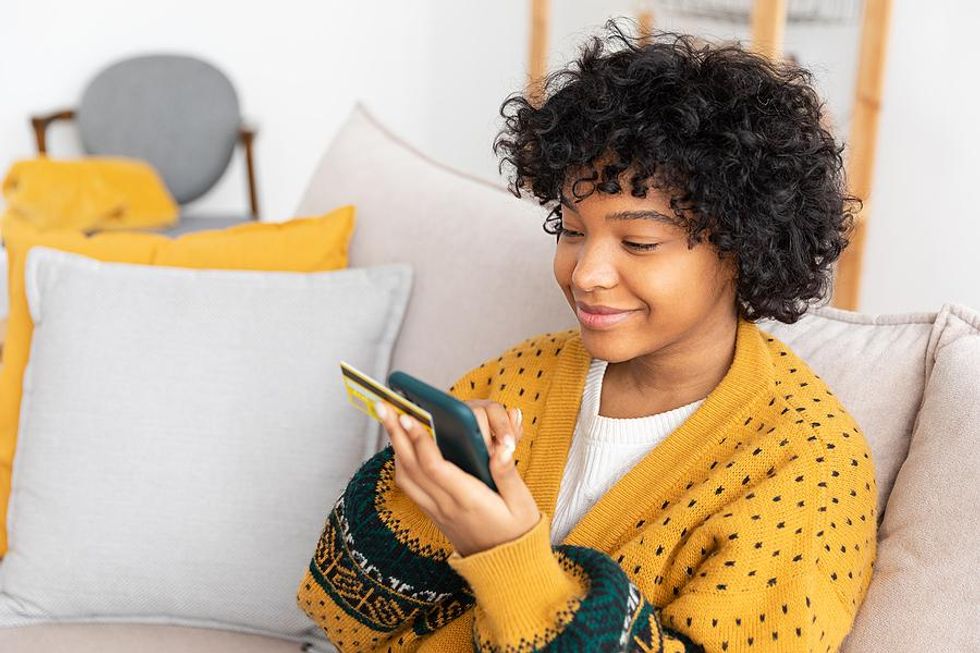 Woman holding her credit card does some online shopping on her phone