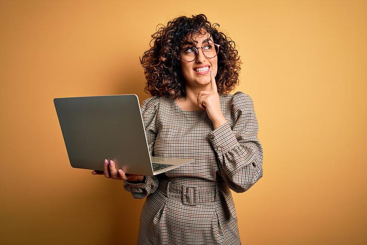 Woman holding laptop thinks about what to put on her resume