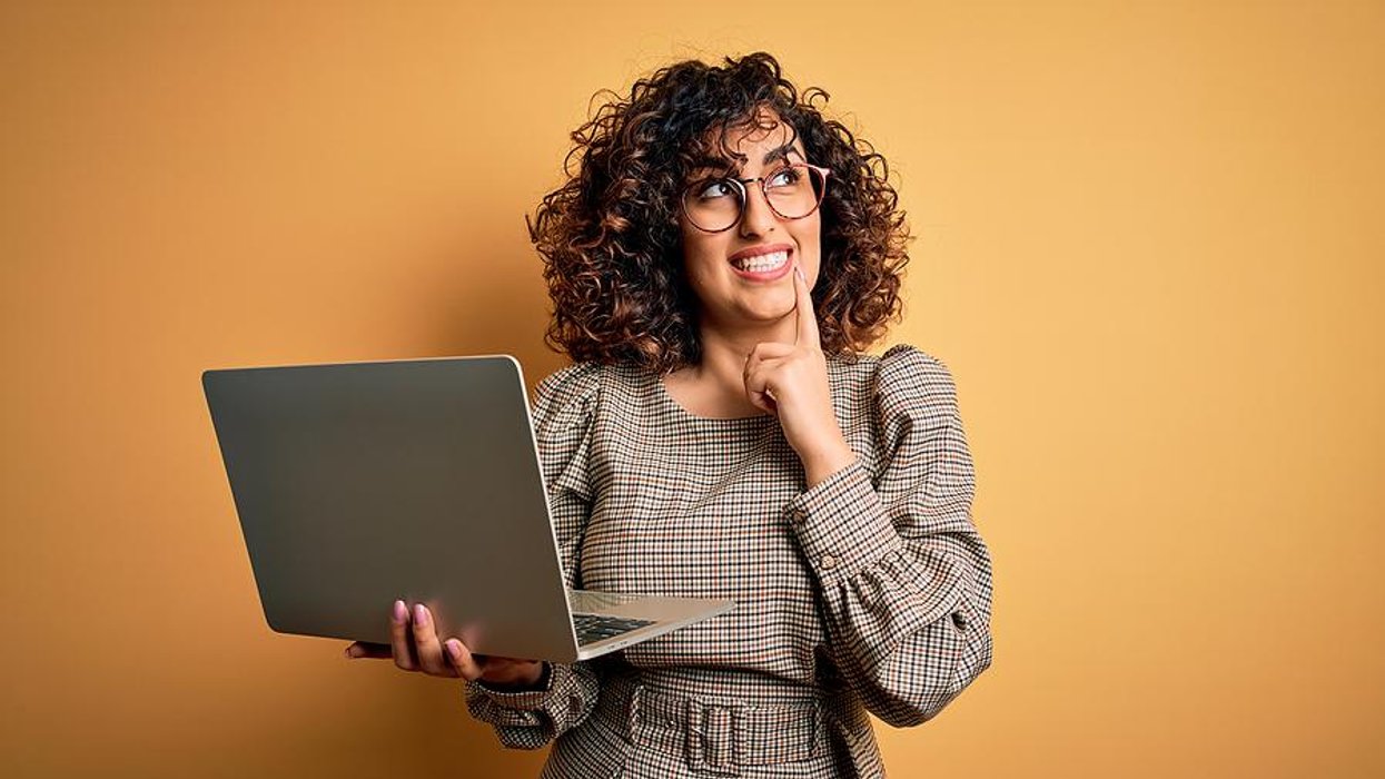 Woman holding laptop thinks about what to put on her resume