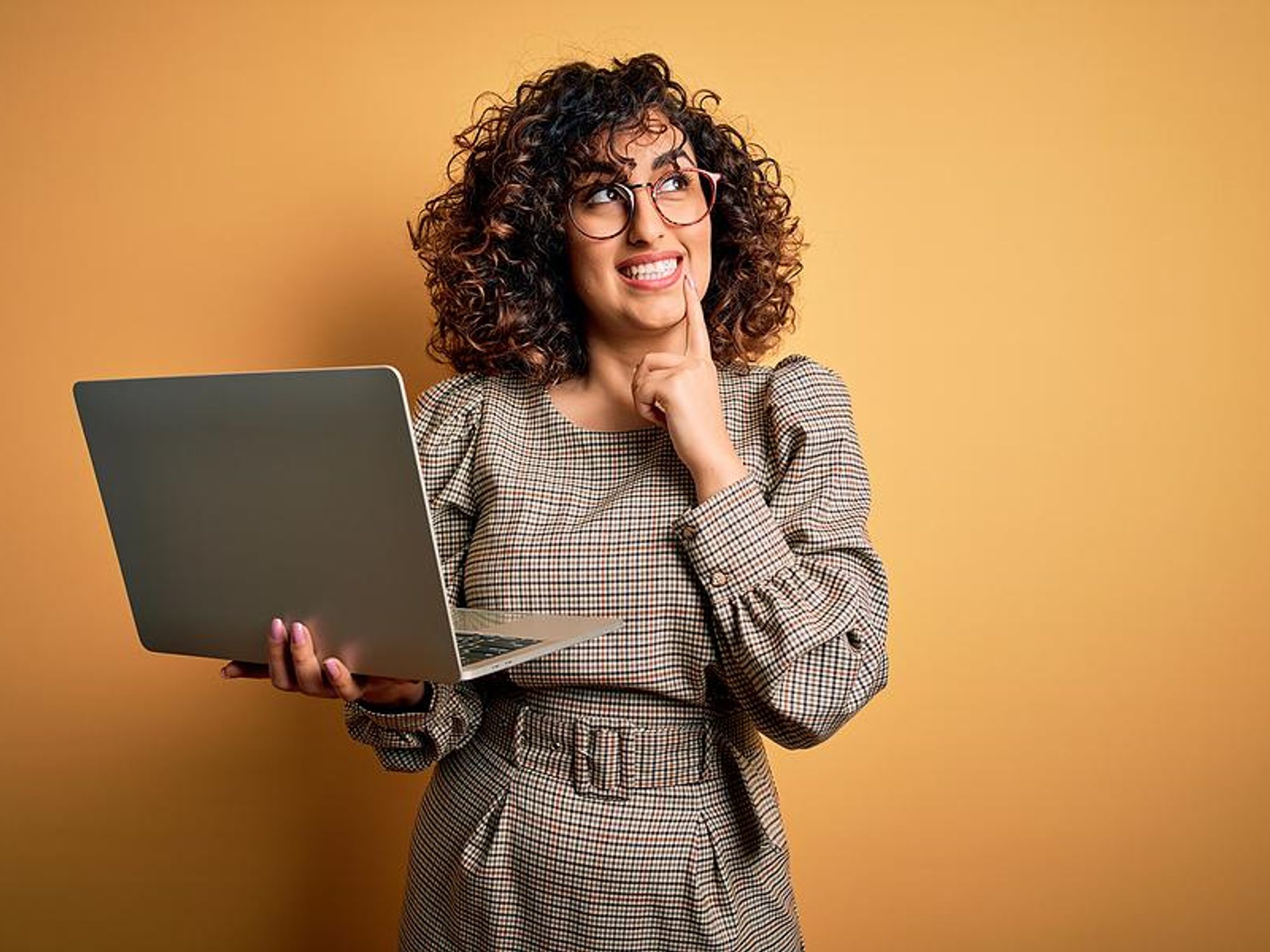 Woman holding laptop thinks about what to put on her resume