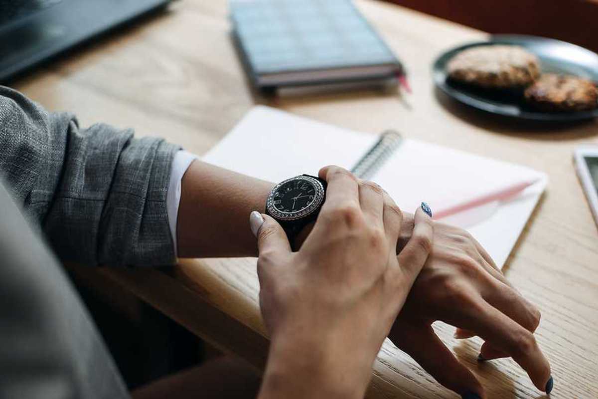 Woman looks at her watch while working, improving her time management with AI