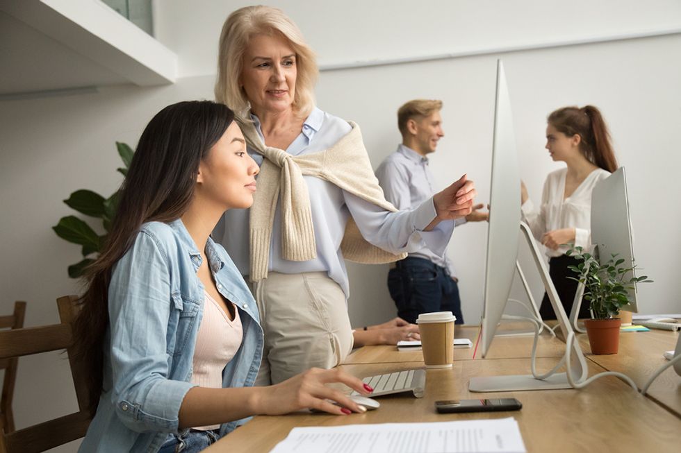 Woman mentors a younger colleague at work