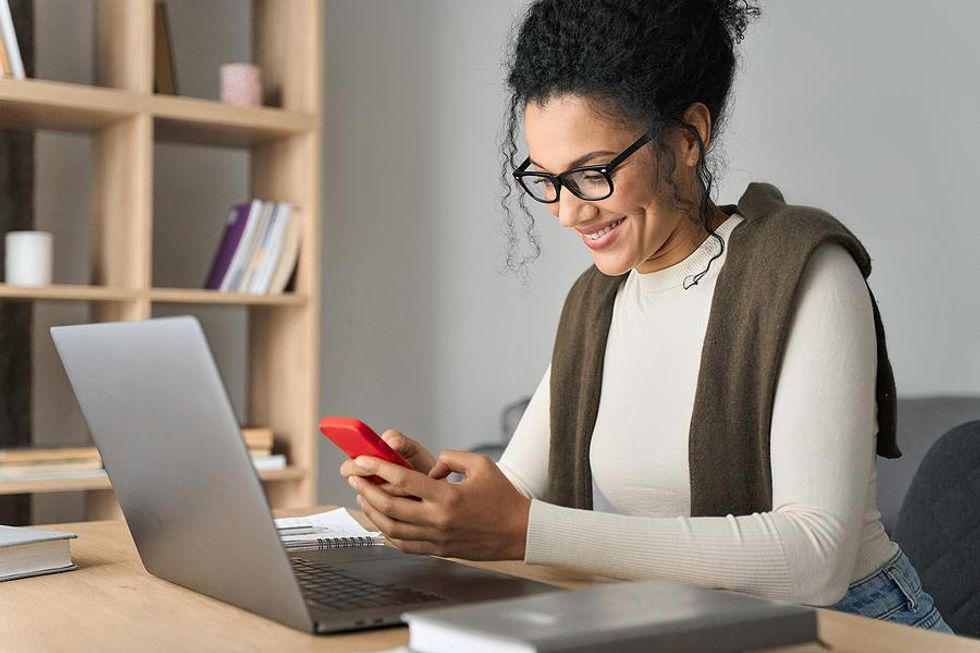 Woman on laptop and phone messages a new connection on LinkedIn
