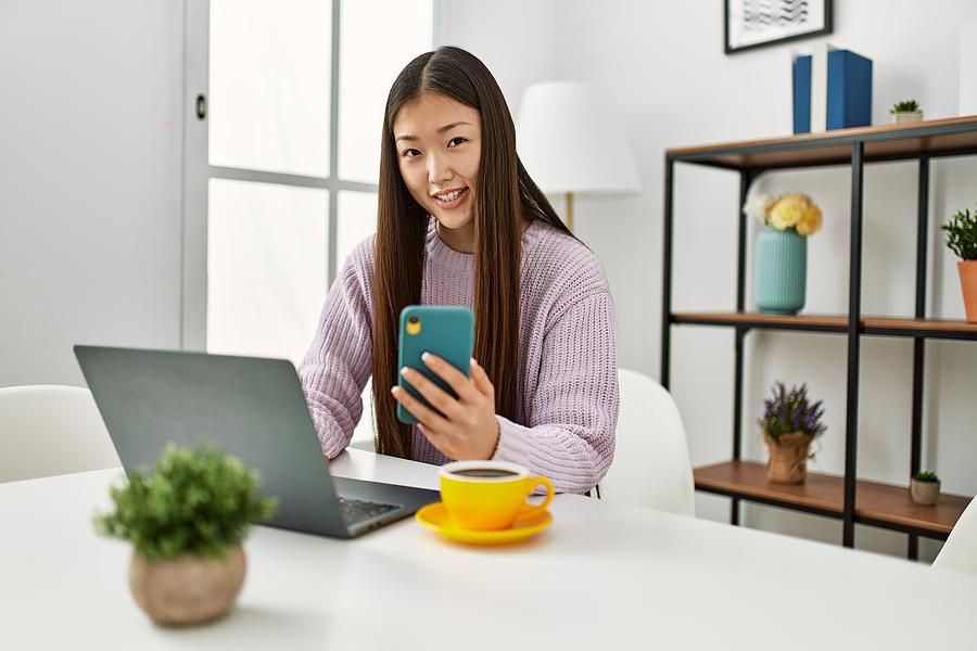 Woman on laptop and phone updates her LinkedIn profile
