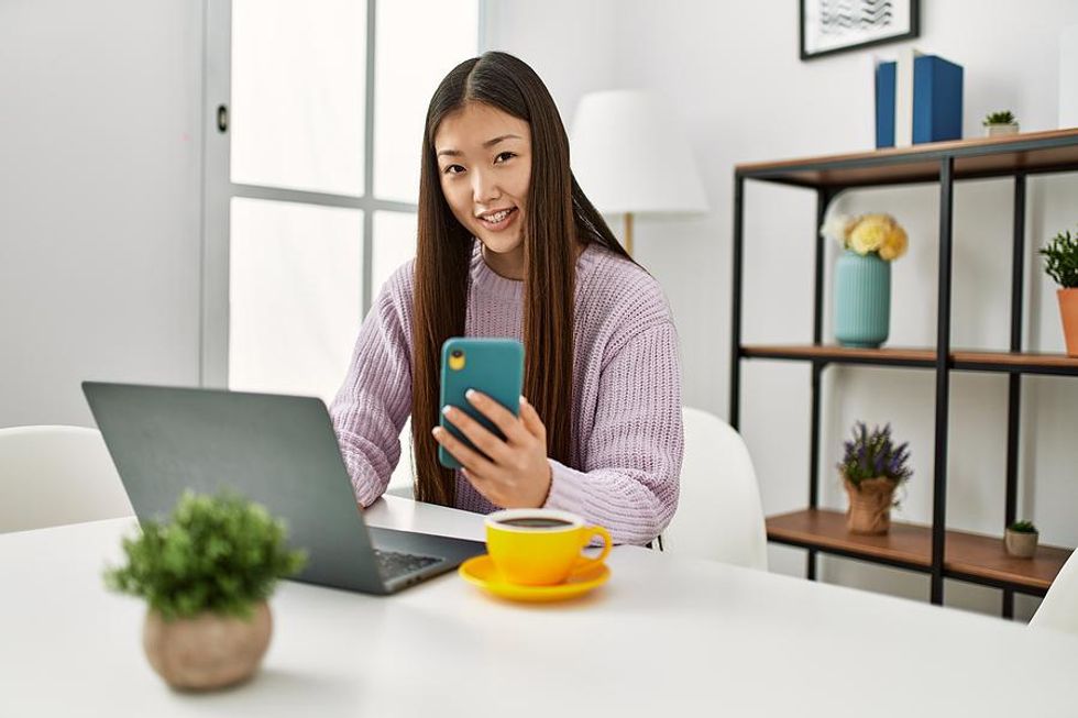 Woman on laptop and phone updates her LinkedIn profile