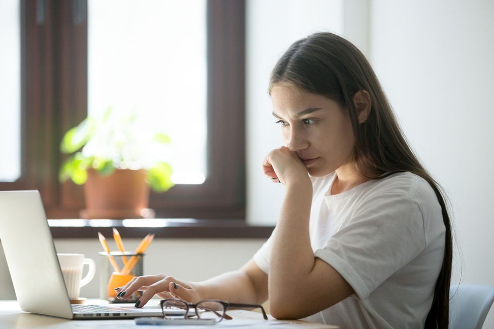 La mujer en la computadora portátil corta la pelusa mientras formatea su currículum
