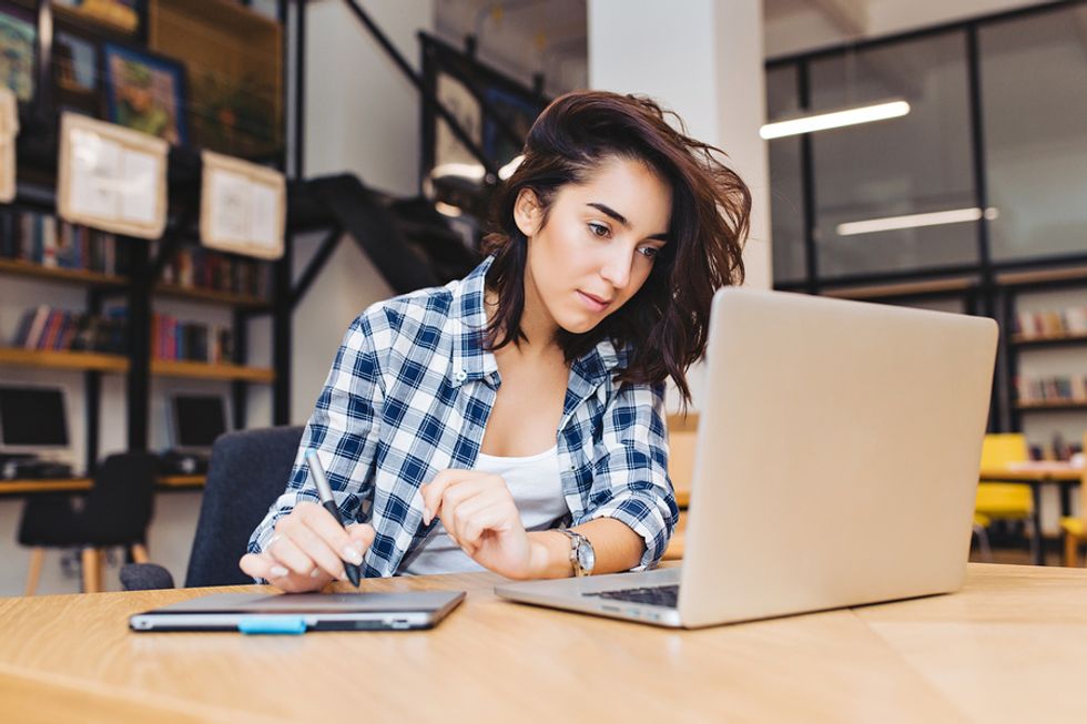 Woman on laptop manages her side hustle while working full time