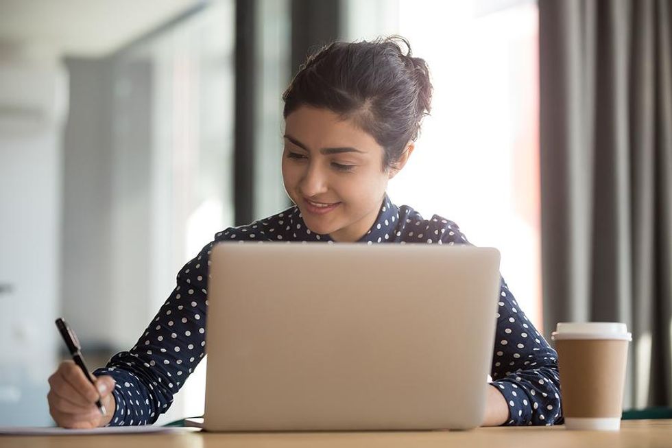 Woman on laptop revises her resume while job hunting