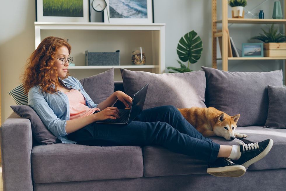 Woman using laptop sitting on sofa while working from home