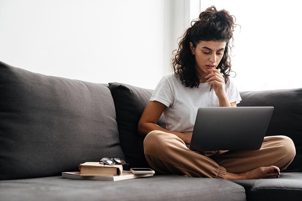 Woman on laptop struggles to write her resume after being fired